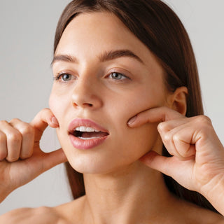 Eine junge Frau mit geöffnetem Mund macht eine Gesichtsyoga Übung.